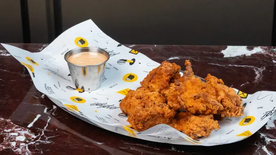 Crispy chicken nuggets with a dip in a steel cup