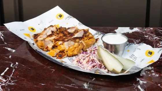 Sliced grilled chicken with coleslaw and a pickle